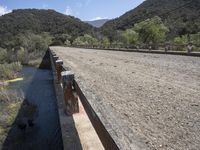 a view from a bridge overlooking trees and a mountain range of hills behind a bridge