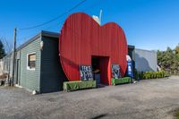 a red apple sign is on the side of a building with garbage and trash bins