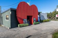 a red apple sign is on the side of a building with garbage and trash bins