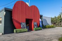 a red apple sign is on the side of a building with garbage and trash bins