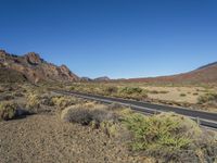 desert landscape with mountains in background, and roadway on it with no passing cars on it