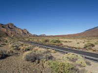 desert landscape with mountains in background, and roadway on it with no passing cars on it