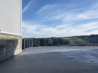 the balcony area of the modern, concreted home in the hills near a town