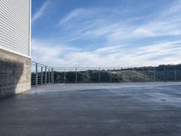 the balcony area of the modern, concreted home in the hills near a town