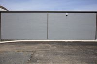 a parking lot with a wall painted a grey block with one red stop sign at the corner