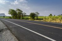 the asphalt road with a white line painted on it is next to a green field