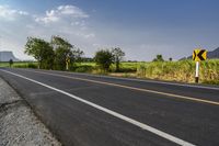 the asphalt road with a white line painted on it is next to a green field