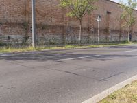 an empty street with grass and buildings near by in a rural town area, on a clear blue day