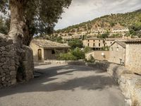 a man walking through a cobbled - in village towards a hill side townhouse