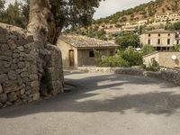 a man walking through a cobbled - in village towards a hill side townhouse