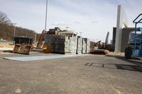 several crates are laid out on a flat surface with crane mounted equipment in the background