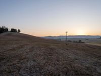 the sun is setting over a hill with a sign on it in front of some hills