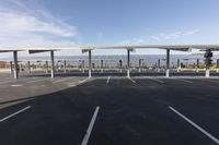 a large parking lot with empty vehicles in it with solar panels on roof and cars parked behind