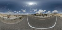 two curved sections of road with clouds in the sky above and street with yellow lines