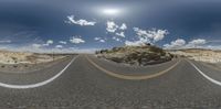 an empty road with some rocks and a sun in the sky, surrounded by a rocky cliff, and in the middle of a desert landscape