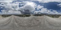 a view from below a road in a desert field with clouds overhead and dirt terrain