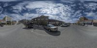 a fish lens image of cars on the street in a city setting with buildings and trees in the background