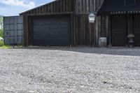 a barn next to a building with two doors and a bicycle leaning against it's wall