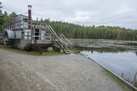 a rustic log house sitting next to a lake and forest area with steps leading to the house