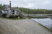 a rustic log house sitting next to a lake and forest area with steps leading to the house