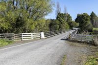 a gate sits on the side of a road next to a wooded area with grass and plants