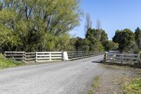 a gate sits on the side of a road next to a wooded area with grass and plants