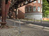 the train station has a rusted steel structure on it's side, with buildings lining the track, along with a brick road and sidewalk