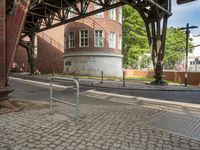 the train station has a rusted steel structure on it's side, with buildings lining the track, along with a brick road and sidewalk