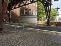 the train station has a rusted steel structure on it's side, with buildings lining the track, along with a brick road and sidewalk