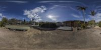 a panorama of an rv parked at a park in the dirt and a man riding a skateboard down the side of a road