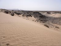 a truck on a dirt road in the desert with rocks and stones on the ground