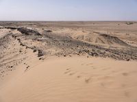 a truck on a dirt road in the desert with rocks and stones on the ground