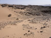 a truck on a dirt road in the desert with rocks and stones on the ground