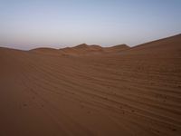 an image of the desert at dusk or sunrise, the horizon view with only one person on the right side