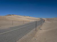 a paved beach with a fence in front of it and the ocean in the distance