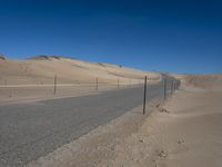 a paved beach with a fence in front of it and the ocean in the distance