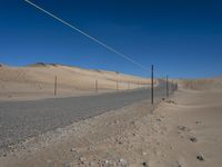 a paved beach with a fence in front of it and the ocean in the distance