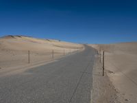 a paved beach with a fence in front of it and the ocean in the distance