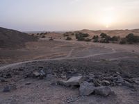 a truck on a dirt road in the desert with rocks and stones on the ground