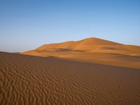 a person walks across the desert with long, thin tracks in the sand dunes of an arid