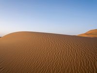 a person walks across the desert with long, thin tracks in the sand dunes of an arid