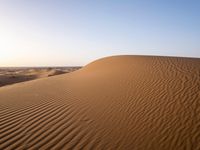 a person walks across the desert with long, thin tracks in the sand dunes of an arid