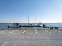 a parking lot with several sailboats docked near it in the water next to some benches