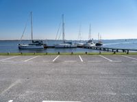 a parking lot with several sailboats docked near it in the water next to some benches