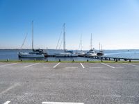 a parking lot with several sailboats docked near it in the water next to some benches