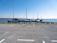 a parking lot with several sailboats docked near it in the water next to some benches