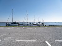 a parking lot with several sailboats docked near it in the water next to some benches