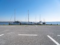 a parking lot with several sailboats docked near it in the water next to some benches