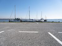 a parking lot with several sailboats docked near it in the water next to some benches