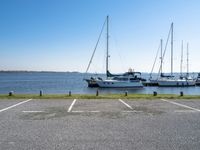 a parking lot with several sailboats docked and a blue sky in the background near the water